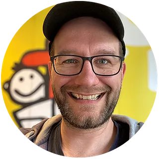 Bastian Basse - Grinsender Mann mit Brille, Bart und Basecap