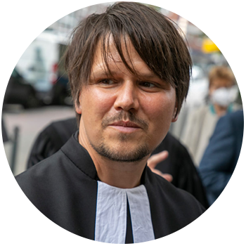 Bastian Basse - Grinsender Mann mit Brille, Bart und Basecap